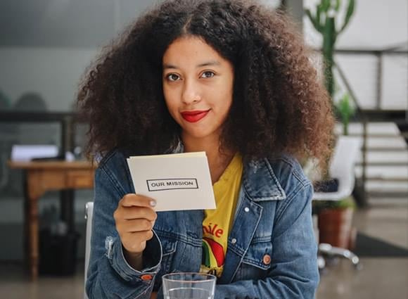 A Mesa participant holding a card that reads Our Mission